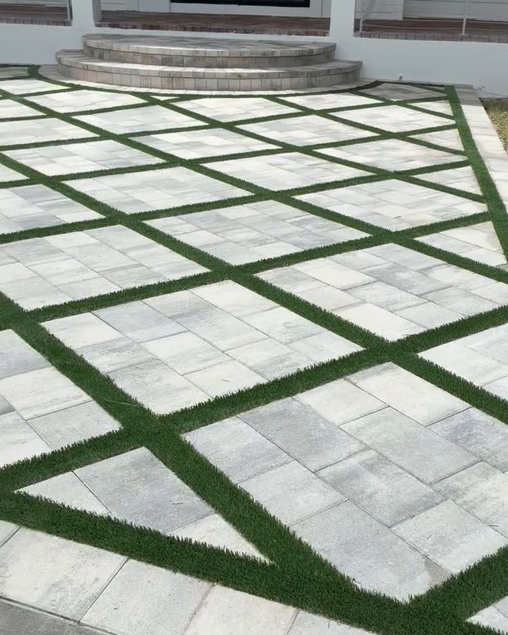 Light gray paver entry along a driveway, laid in a diamond pattern with green turf joints
