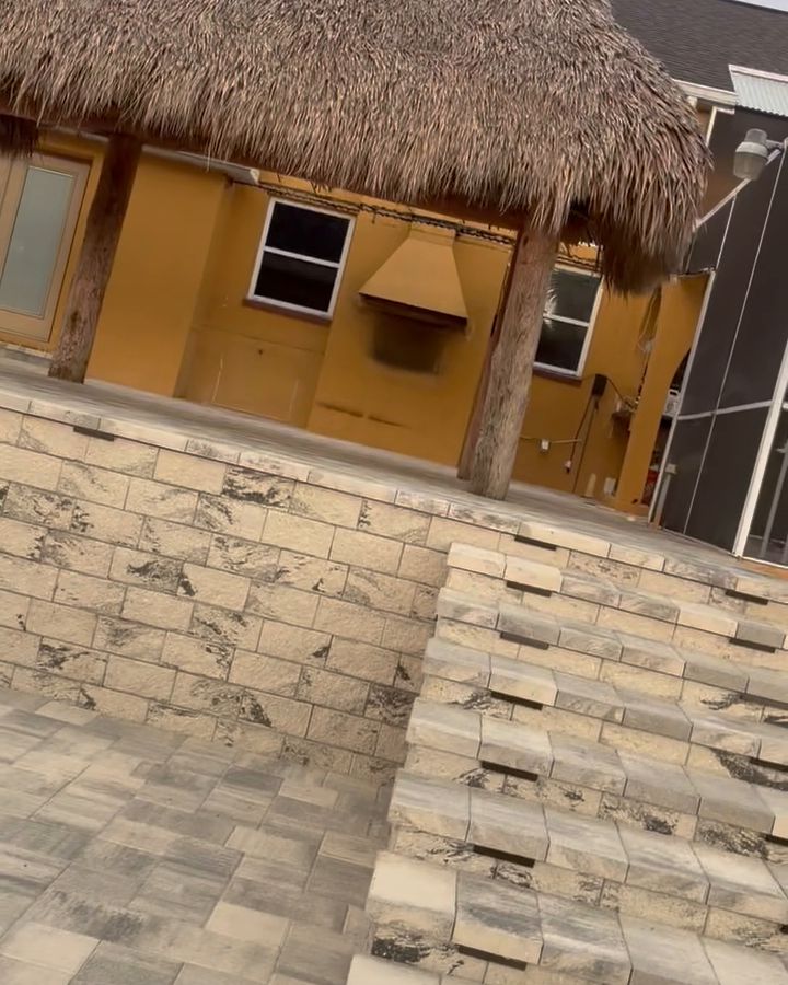 Stone retaining wall and stacked stone steps above a paver patio