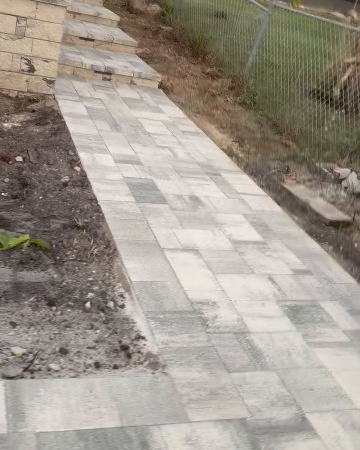 Paver walkway running alongside a house to stone steps